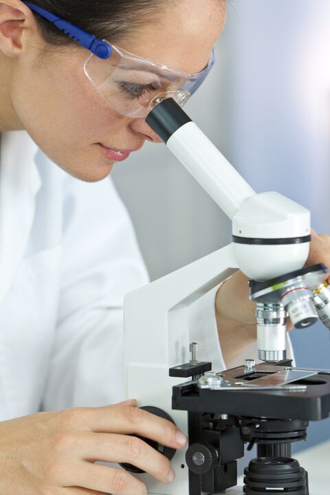 a woman looks through a microscope